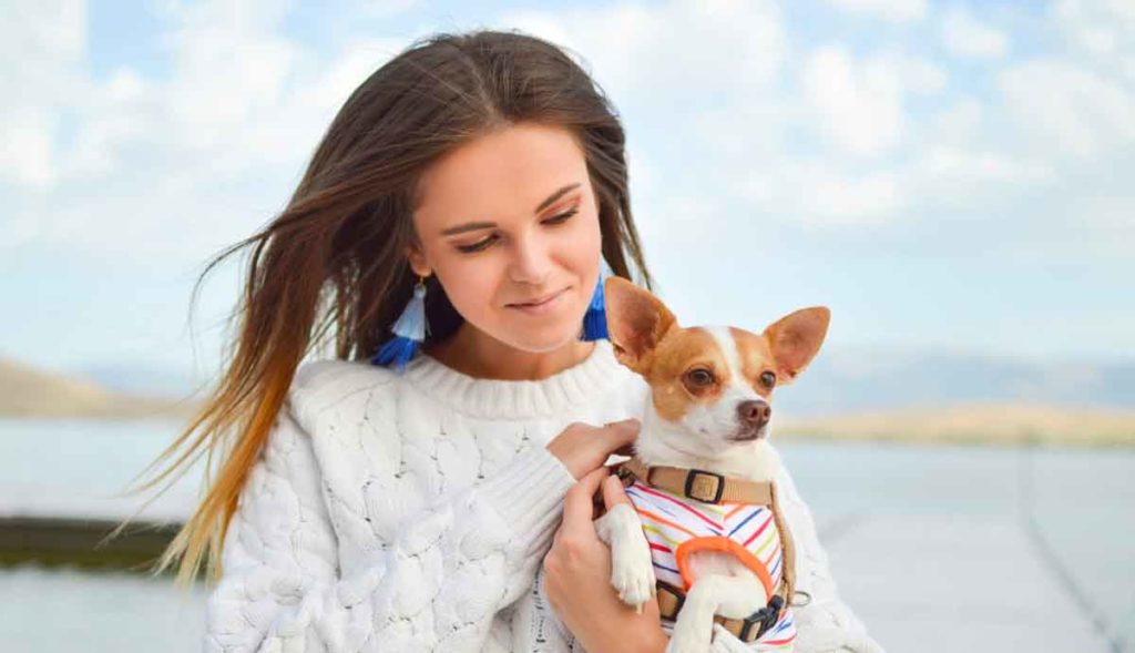 Woman hugs her small dog.